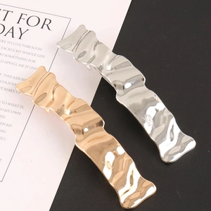 Detailed view of wave-shaped alloy hair clips in gold and silver with metal texture