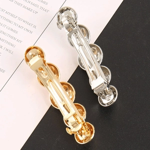 Polished gold and silver beaded metal hair clips set with spring mechanism on elegant background