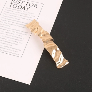 Macro shot of a golden wavy metal hair clip on a white card with black background