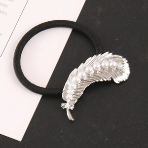 Detailed macro of vintage silver alloy feather charm hair tie with white pearls