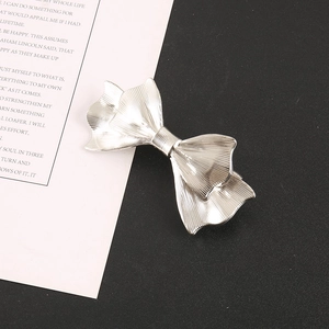 Close-up of a silver bow hair clip with textured metallic finish and spring fastener