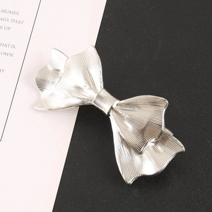 Elegant silver metal bow hair clip with pleated texture on a modern black and white background