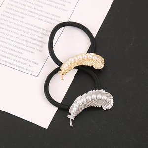 Detailed macro view of vintage feather hair ties with white pearls and gold accents