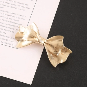 Macro shot showing the gold bow hair clip with textured vertical stripes and metal finish