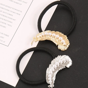 Detailed macro view of gold and silver feather charms with pearls on elastic hair ties