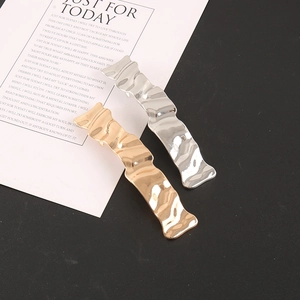 Detailed close-up of wavy gold and silver metal hair clips with a polished texture