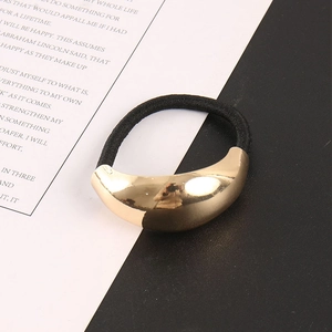 Detail eines hochelastischen schwarzen Haargummis mit poliertem goldenem Metallornament