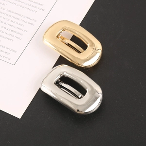 Detailed shot of polished gold and silver rectangular metal hair clips on a stylish background