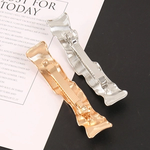 Detailed view of wavy metallic gold and silver hair clips on a black and white background