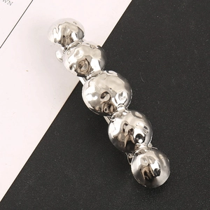 Minimalist silver ball-shaped metal hair clip with hammered texture on dual background