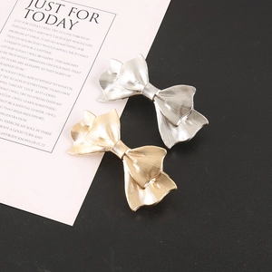 Detailed macro view of gold and silver bow hair clips with vertical striped metal texture
