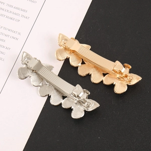 Macro detail of gold and silver butterfly hair clips showing the spring back mechanism