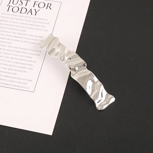Detailed macro view of silver wavy metal hair clip with irregular pleated texture design