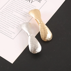 Macro detail of gold and silver bow hair clips with brushed metal texture and glitter finish