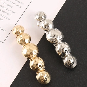 Detailed view of bead-shaped alloy hair clips in gold and silver with hammer texture