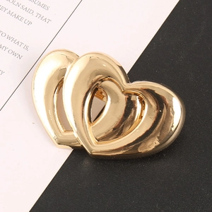 Broche élégante double cœur dorée avec une finition métallique polie sur fond minimaliste