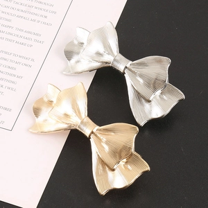 Detail showing gold and silver metal bow hair clips with elegant vertical stripe texture