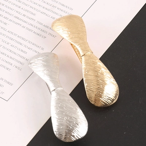 Detail of brushed metal bow hair clips in gold and silver showing fine texture