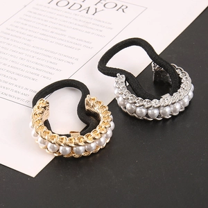 Close-up of pearl metal chain hair ties in gold and silver on a textured background