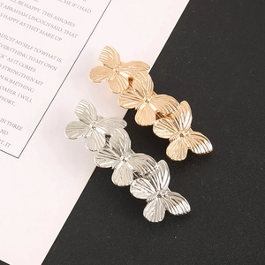 Detail view of gold and silver metallic butterfly hair clips with 3D wings and textures