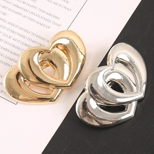 Détail d'accessoires en forme de cœur superposés en alliage d'or et d'argent sur papier