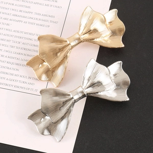 Detailed view of metal bow hair clips in gold and silver with elegant vertical texture