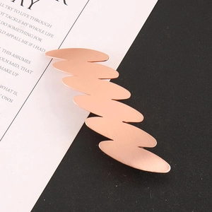 Dettaglio del fermaglio per capelli in metallo oro rosa ondulato con finitura opaca