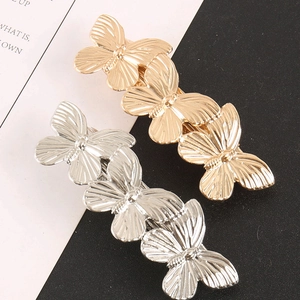 Detail of gold and silver butterfly hair clips with textured wings and metallic finish