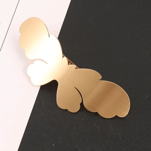Detail of a matte golden butterfly hair clip with a smooth metallic satin finish