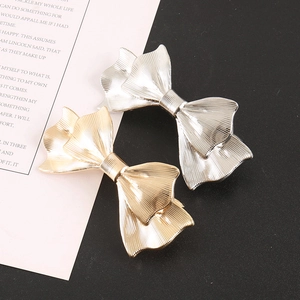 Detailed view of large metal bow hair clips in gold and silver with ribbed texture