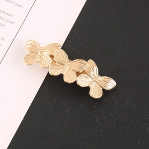 Detailed view of golden butterfly hair clip with polished metallic wing textures
