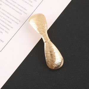 Macro shot of gold-tone geometric metal hair clip showing a fine brushed texture finish