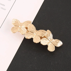 Detailed close-up of three golden butterflies hair clip with fine textured metallic wings