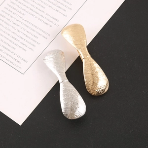 Close-up of geometric gold and silver alloy hair clips with textured brushed metal finish
