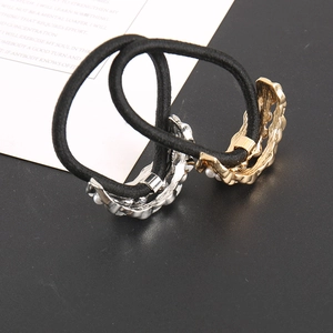 Close-up of black elastic hair ties with gold and silver pearl-embellished accents