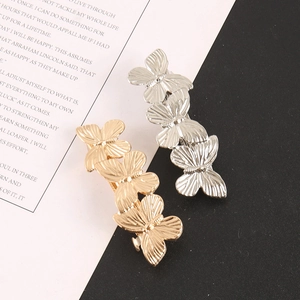 Detail view of gold and silver triple butterfly hair clips on a monochrome background