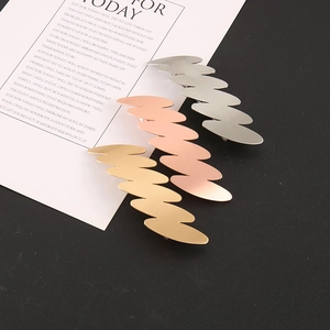 Dettaglio di tre fermagli per capelli ondulati in lega nei colori oro, oro rosa e argento