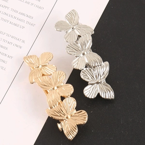 Detail of gold and silver butterfly hair clips with textured wings on a stylish backdrop