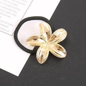 Close-up of golden metal flower charm and black high-elasticity hair tie on a ring