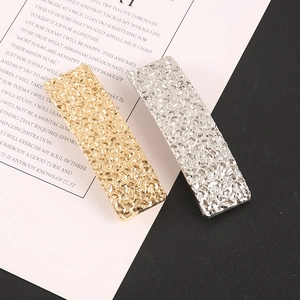 Détail de barrettes rectangulaires dorées et argentées avec texture métallique givrée