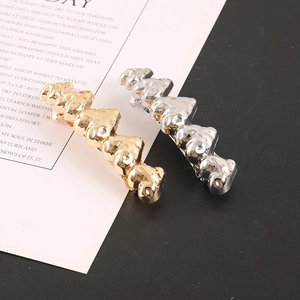 Détail de barrettes ours dorées et argentées avec une finition en métal poli brillant