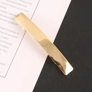 Detailed macro shot of a sleek rectangular metal hair clip with a polished gold finish