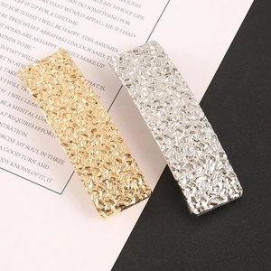 Détail de barrettes à cheveux dorées et argentées avec texture glacée et fini métallique