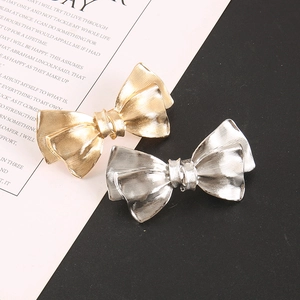 Detailed view of layered metallic bow hair clips in gold and silver with brushed texture