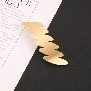 Dettaglio del fermaglio per capelli ondulato dorato in lega su carta decorativa