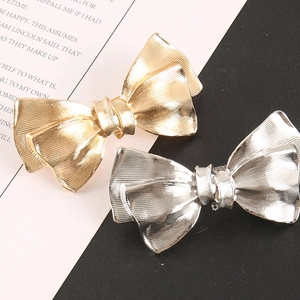 Detail view of gold and silver metallic bow hair clips with textured brushed finish