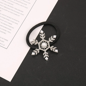 Macro shot of black elastic hair tie with silver rhinestone snowflake and faux pearls
