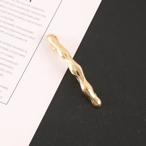 Detail einer goldenen Wellen-Haarklammer mit glänzendem Finish auf modernem Hintergrund