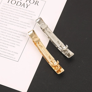 Macro detail of glossy gold and silver minimalist metal hair clips on a modern background