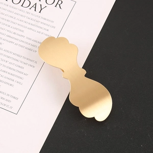 Detailed view of light gold hair clip featuring brushed metal texture and wave bow design